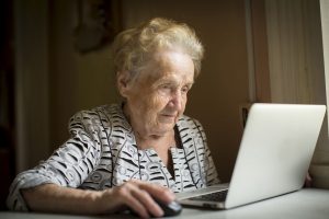 45393059 - old woman sitting with laptop at table in his house.