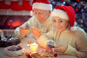 65629480 - portrait of smiling senior couple in santa hats preparing for christmas in the evening